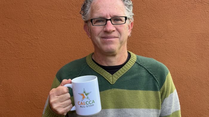 Dan Lieberman holding a CalCCA All-Star mug
